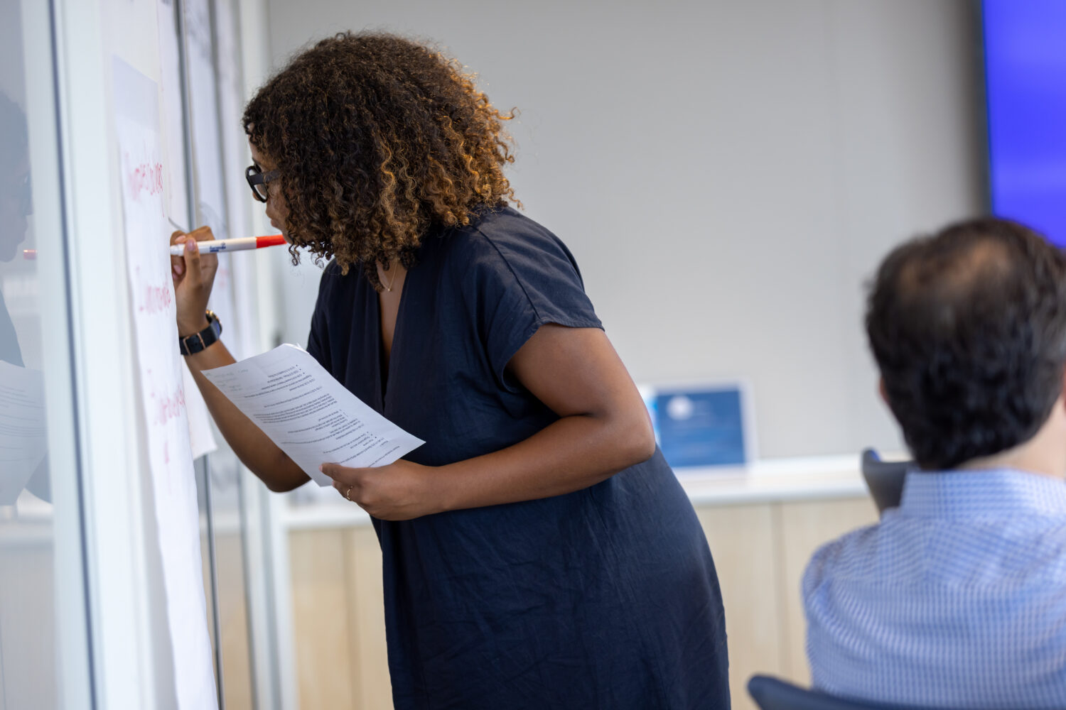 A woman writes on post-it note on the wall.